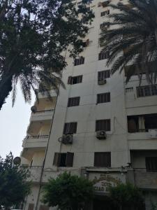 un edificio alto de color blanco con ventanas y palmeras en Ciao Hotel Cairo, en El Cairo