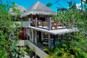 a house with a thatched roof and a deck at Villa Feronia Tulum in Tulum