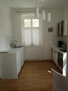 een witte keuken met een wastafel en een raam bij Ferienwohnungen Wilhelm in Bad Schandau
