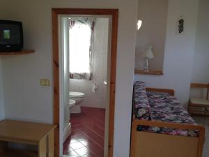 a bedroom with a bed and a toilet and a window at Hotel Pini in Corniolo