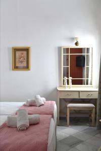 una camera con 2 letti, una scrivania e uno specchio di Hara Studios and Apartments a Naoussa