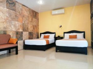 a hotel room with two beds and a chair at Departamentos X`Kanlol in Izamal