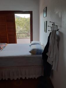 een slaapkamer met een bed en een raam met uitzicht bij Casa no Centro Histórico de Pirenópolis in Pirenópolis