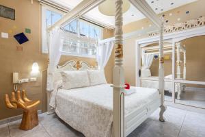 1 dormitorio con cama blanca con dosel y ventana en Los MOXAICOS, TENERIFE, en Costa del Silencio