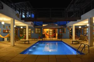 a pool at night with chairs and an umbrella at Pousada Costa Prestige in Touros