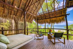 a bedroom with a bed and a chair on a deck at Morgan's Rock in San Juan del Sur