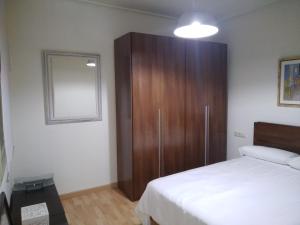 1 dormitorio con 1 cama y armario de madera en YEDRA en Ourense