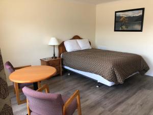 a bedroom with a bed and a table and chairs at Century Motel in Cornwall