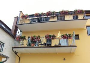 a yellow building with a balcony with flowers on it at Marktplatz Traunsee LAKE View in Gmunden