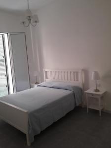 a white bedroom with a bed and a window at Renda Apartments in Trapani