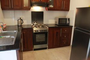 a kitchen with wooden cabinets and a stove and a microwave at Dominic's best in Mount Lavinia