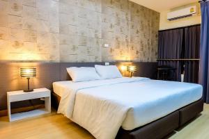 - une chambre avec un grand lit blanc et deux lampes dans l'établissement Prajaktra City Hostel, à Udon Thani