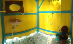 a yellow bathroom with a sink and a shower at 4 Pohon - Les 4 Arbres in Pandang