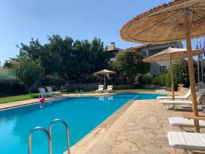 a swimming pool with chairs and umbrellas at Elianthos Villas in Vamos