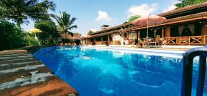 a swimming pool next to a house with an umbrella at Villa Sumbing Indah in Magelang