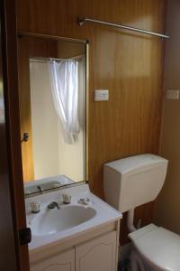 a bathroom with a sink and a toilet and a mirror at Lani's Holiday Island in Forster