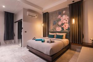 a bedroom with a large bed with a painting on the wall at Na Vela Village - Adults Only Hotel in Ko Lanta