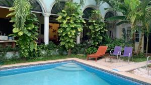 a swimming pool with two chairs and a house at Hotel Santa Ana in Mérida
