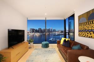 a living room with a couch and a large window at Orange Stay at Collins Wharf in Melbourne