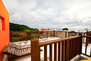 a wooden balcony with a bench and the ocean at Kenting Shen's Homestay in Eluan