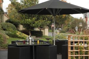 a black table with an umbrella on a patio at Grosvenor Hotel in Stratford-upon-Avon