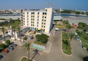 a large white building with palm trees and a parking lot at Best Western Hotel Nettuno in Brindisi