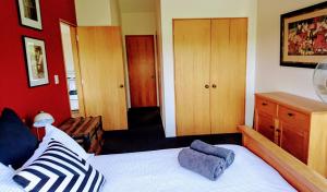 1 dormitorio con cama y pared roja en Shelly Beach Studio, Waiheke Island, en Auckland