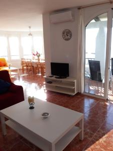 een woonkamer met een witte tafel en een tv bij Rocamar 2 in Cala Morell