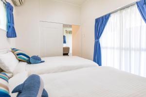 本部町にあるビィラピシーヌ瀬底 -SEVEN Hotels and Resorts-の青いカーテンが備わる客室のベッド2台