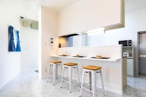 une cuisine blanche avec deux tabourets et un comptoir dans l'établissement Villa Piscine SESOKO -SEVEN Hotels and Resorts-, à Motobu