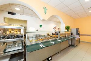 two people in a kitchen preparing food in a kitchen at Casa per Ferie Opera Don Calabria in Rome