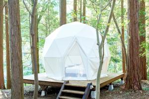 tenda su una piattaforma di legno nel bosco di 泊まれる公園 INN THE PARK a Numazu
