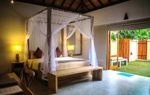 a bedroom with a canopy bed with a bench at The Spice Trail in Arugam Bay