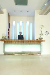 Regency Hotel Malabar Hill في مومباي: رجل في بدلة يجلس في مكتب الاستقبال