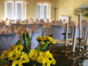 a table with yellow flowers and candles on it at Hainberg Hotel Garni in Habrachćicy