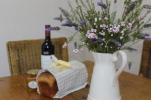 - une bouteille de vin et un vase de fleurs sur une table dans l'établissement Kandelaars Cottage, à Oudtshoorn 30 autres photos