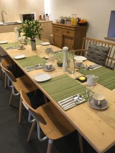 a large wooden table with green place mats on it at Westbury Cross House Bed & Breakfast in Westbury-sub-Mendip