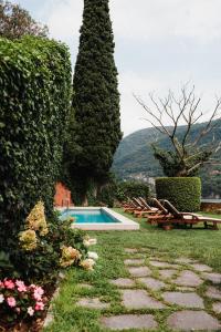a swimming pool in a garden with trees and flowers at Regina Teodolinda Suites in Laglio