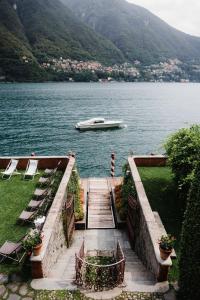 a boat on a lake with a dock and chairs at Regina Teodolinda Suites in Laglio