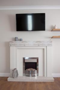 a living room with a fireplace with a flat screen tv above it at Cwtch Y Coetir in Swansea
