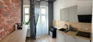 a kitchen with white cabinets and a brick wall at Apartament Równa 12 in Kielce