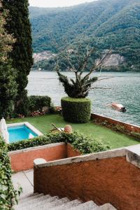 a garden with a swimming pool next to a body of water at Regina Teodolinda Suites in Laglio