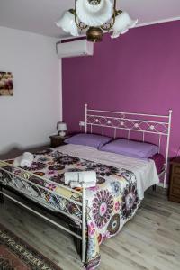 una camera con un letto con una parete viola di LA VIGNA FIORITA B&b a Tarzo