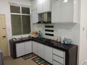 a kitchen with white cabinets and a black counter top at Z&M homestay in Jertih