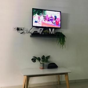 una TV a parete con tavolo e pianta di Z&M homestay a Jertih