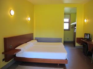 a bedroom with a bed and a yellow wall at Cova Da Balea in Aldán