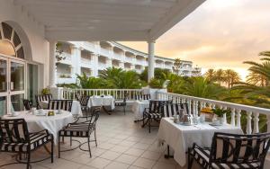 a restaurant with white tables and chairs on a balcony at OCEANA Hotel & Spa in Hammamet