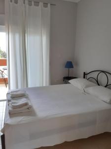 uma cama branca num quarto com uma janela em Maria-Villa em Psakoudia