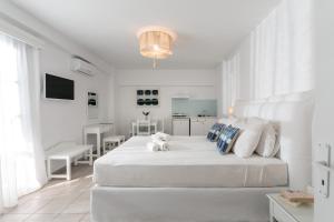 a white bedroom with a large bed with a teddy bear on it at Ippokampos Beachfront in Naxos Chora