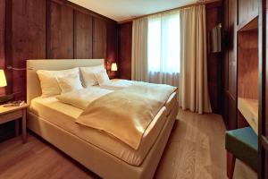 a bedroom with a large bed and a window at Zur Post Residence Sexten in Sesto